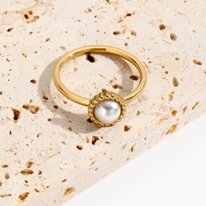 Elegant gold plated stainless steel ring with pearl detail on travertine stone