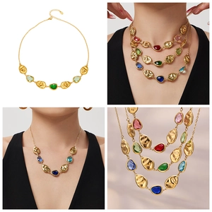 Close-up of gold chain with multi-colored pear-cut glass stones and textured charms