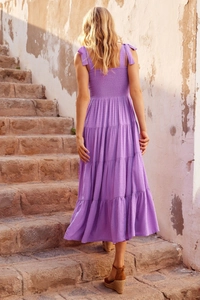 Detail of purple backless tiered dress showing ruffle texture on a stone staircase