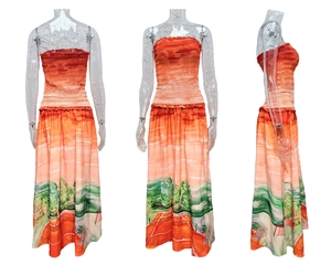 Detail of strapless beach maxi dress featuring vibrant coastal landscape print and pleated hem