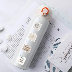 White vacuum flask with orange lock decorated with vintage inspirational stickers