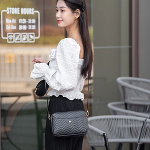 Detail of black V-quilted crossbody bag with a detachable mini round coin purse