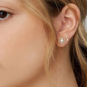 Close-up of elegant gold plated sunburst earrings with emerald cat-eye stone and zircons