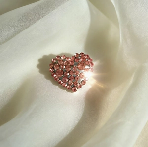 Sparkling pink rhinestone heart brooch with silver metal base on soft silk background