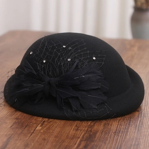 Detail of elegant black wool felt pillbox hat with feathers, mesh veil and rhinestones