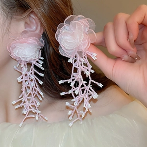 Detailed view of pink mesh flower earrings with dangling pearl bead tassels on a model