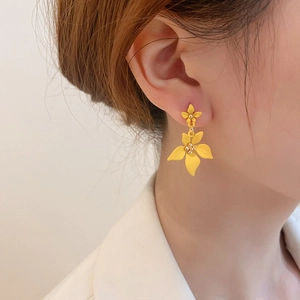Close-up of yellow flower drop earrings with matte finish on a female model