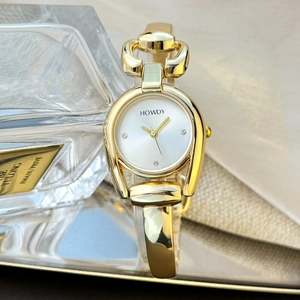 Close-up of golden horseshoe watch case with rhinestone dial and bangle bracelet