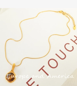 Detail shot of the golden chain necklace featuring a round brown tiger eye stone pendant