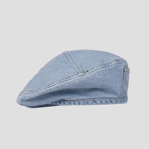 Detailed side view of washed blue denim beret with orange stitching and pocket