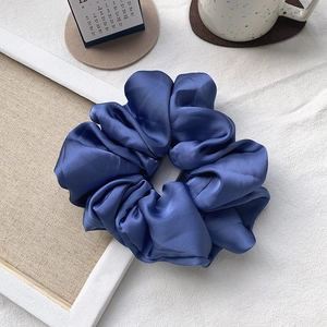 Macro detail of navy blue satin oversized scrunchie showing glossy pleated fabric texture