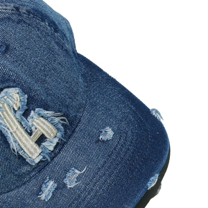 Macro shot of vintage washed blue denim baseball cap with distressed hole details and LA embroidery