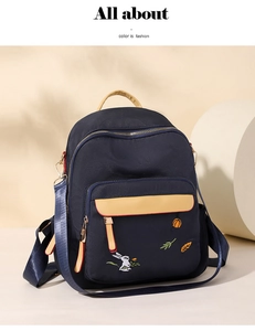 Detail of navy canvas backpack with yellow pocket and elegant leaf embroidery motifs