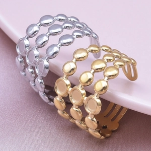 Detail of gold and silver triple-layered open rings with round disc charms on purple silk