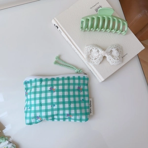 Détail d'un porte-monnaie en coton à carreaux verts avec motifs floraux et fermeture