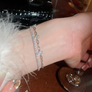 Detail of double-layered silver bracelet with zircon flowers and star charm on wrist