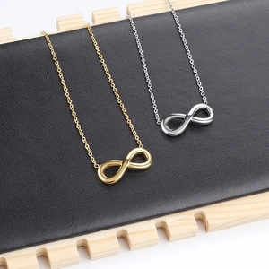 Primer plano de collares con símbolo de infinito en oro y plata sobre soporte negro