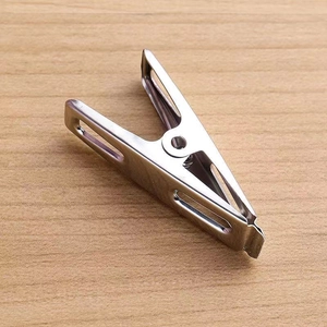 Macro view of stainless steel clip with strong spring on a light wood background