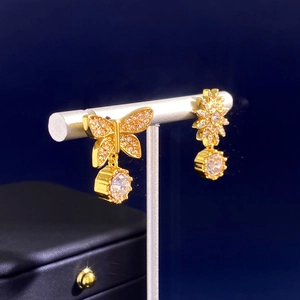 Macro view of asymmetric golden butterfly and star earrings with pavé crystals