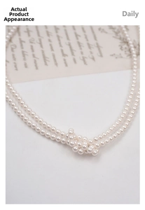 Close-up of double-layer white pearl necklace with elegant twisted knot design