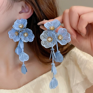Close-up of light blue flower tassel earrings with rhinestone centers on a model
