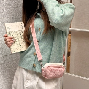 Detail of pink nylon crossbody bag featuring delicate embroidered bows and soft strap
