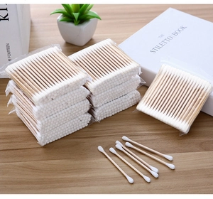 Detail of dual-tipped wooden cotton swabs for makeup and hygiene on a wooden table