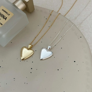 Detail of silver and gold heart necklaces on a ceramic tray with a perfume bottle
