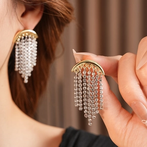 Close-up of sparkling rhinestone tassel earrings with a crescent moon design