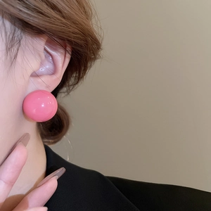 Close-up of a minimalist pink spherical stud earring on a model for a stylish look