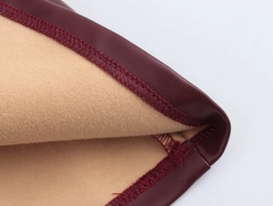 Detail of burgundy PU leather fabric with beige faux suede lining and reinforced stitching