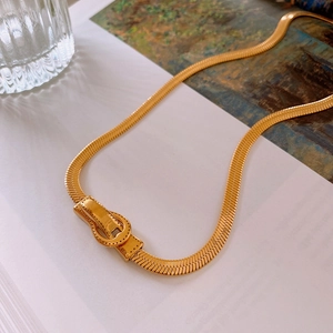 Détail d'un collier chaîne serpent dorée avec fermoir boucle sur fond artistique