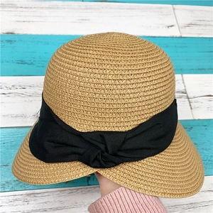 Dettaglio del cappello di paglia intrecciata con fiocco nero e consistenza elegante