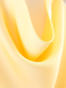 Gros plan sur le tissu en satin de soie jaune vif montrant texture et drapé fluide