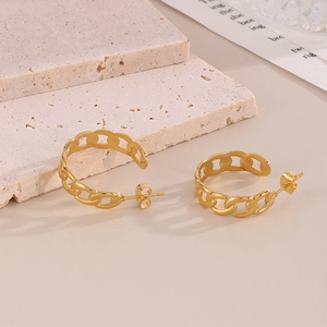 Détail de boucles d'oreilles maillons plaqué or sur un présentoir en pierre texturée