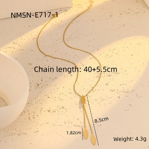 Detailed view of a gold leaf pendant necklace with size measurements on a beige surface