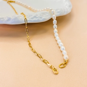 Detail of necklace featuring a gold paperclip chain and white freshwater pearls