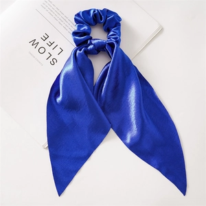 Detailed close-up of Royal Blue satin hair scrunchie with long ribbon on a white magazine