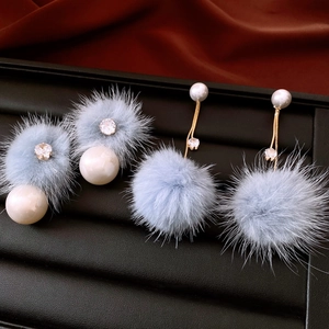 Dettaglio orecchini di perle placcati oro 18K con pompon azzurri e piccoli cristalli lucidi