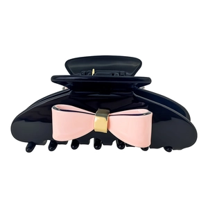 Close-up of black acetate hair claw clip featuring a pink bow and gold metal buckle