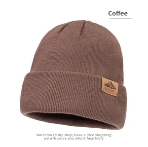 Close-up detail of coffee knit beanie with a mountain logo embossed on a leather patch