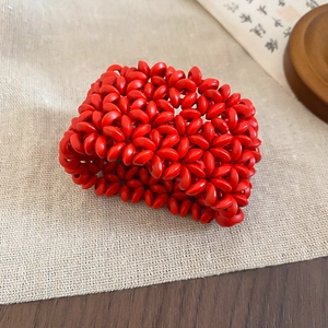 Macro shot of red hand-woven bead bracelet on gray linen with vintage calligraphy decor
