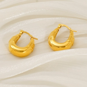 Boucles d'oreilles créoles dorées en U avec texture vintage sur fond de soie