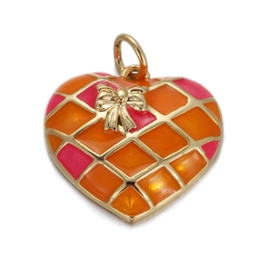 Close-up of golden heart pendant with orange and pink enamel patterns and bow detail