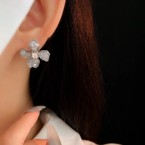 Dettaglio di orecchini a fiore in argento con cristalli grigi indossati da una modella