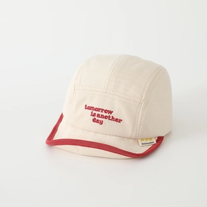 Close-up of baby cotton cap with red piping and tomorrow is another day embroidery
