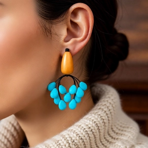 Close-up of ethnic style teardrop tassel earrings with orange and blue beads on a model