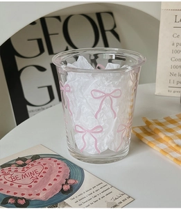 Detail of a transparent glass cup with a pink bow pattern in a lifestyle setting