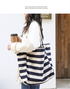 Navy blue and white striped canvas tote bag shown in a casual street style lifestyle view
