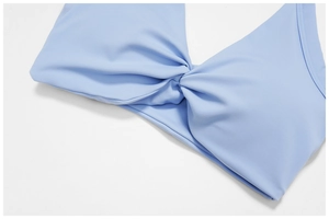 Close-up of light blue sports bra featuring a twist-front design and smooth knit fabric
